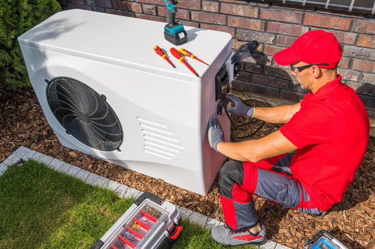 Guy repairing air source heat pump, stock image
